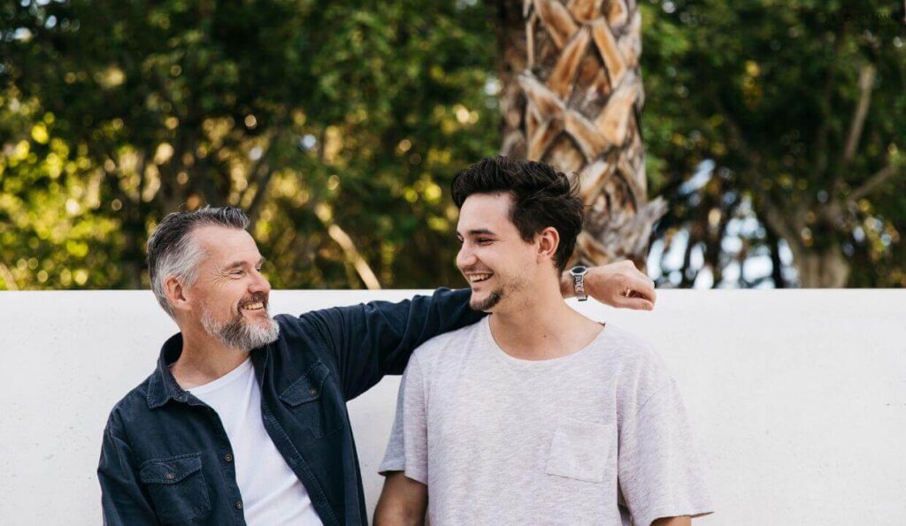 A father and son infront of a wall.