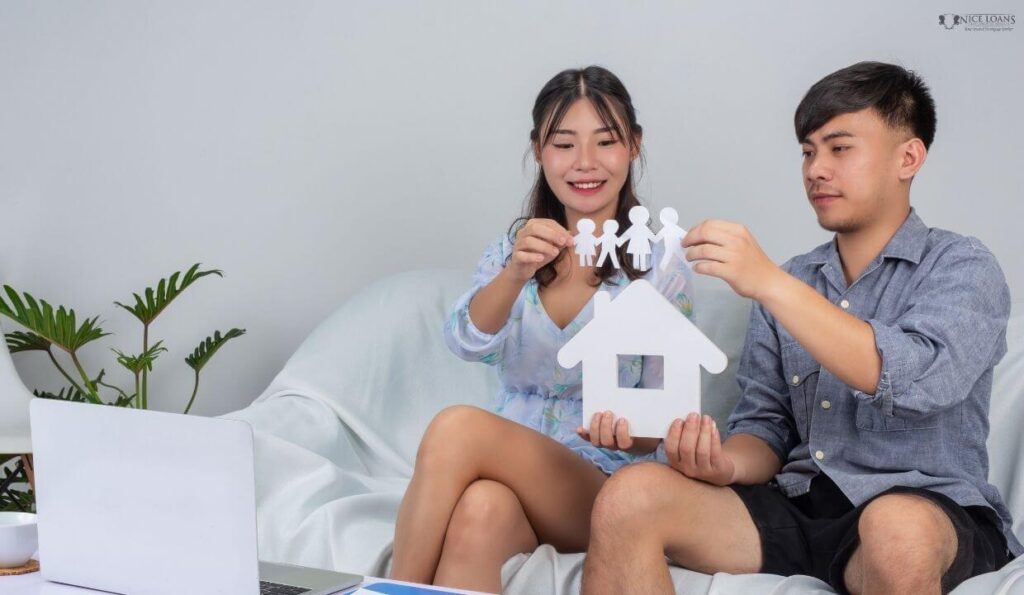 a young couple with a model home made of paper in their hands. 