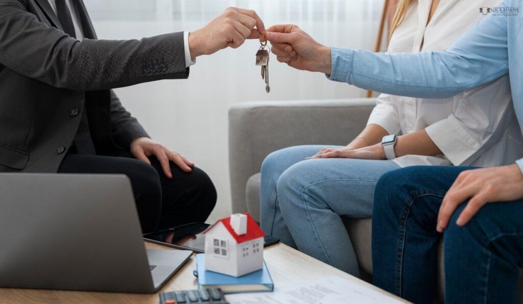 A man in a suit handing out home keys over to a couple.