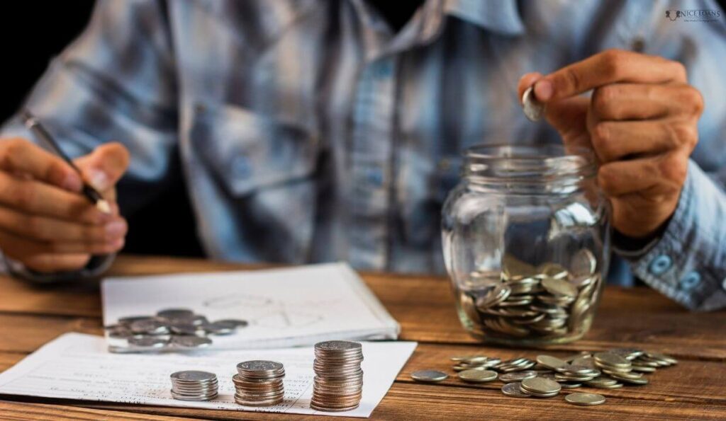 A man is putting coins inside a glass jar. 