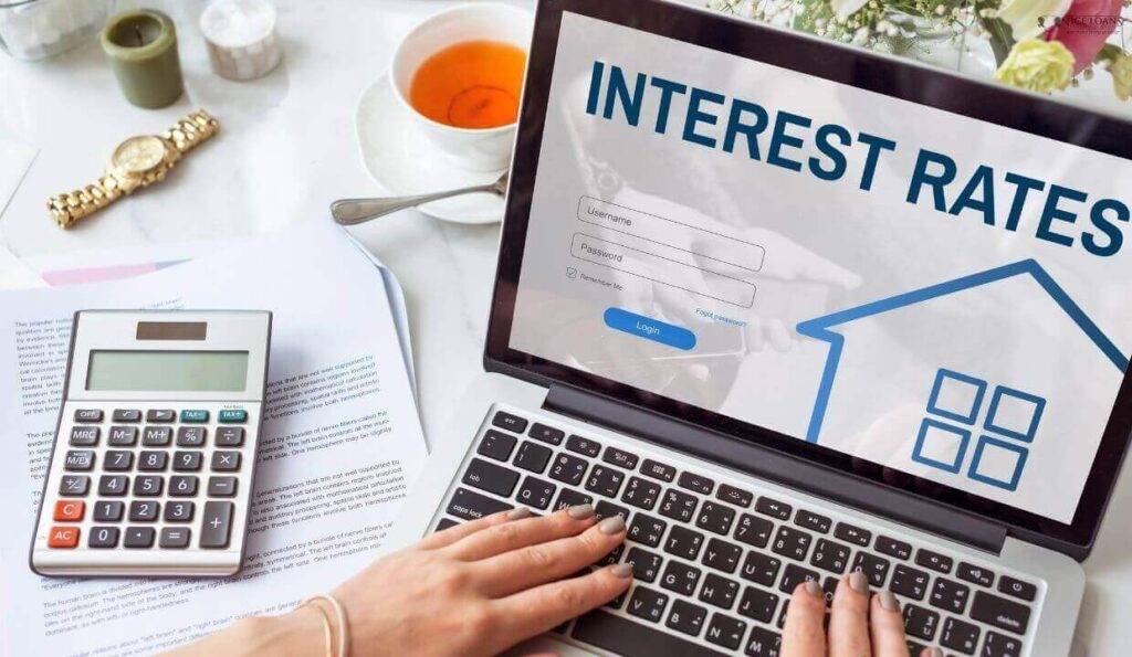 a laptop with a lady typing on it and some documents beside it with a calculator on top. 