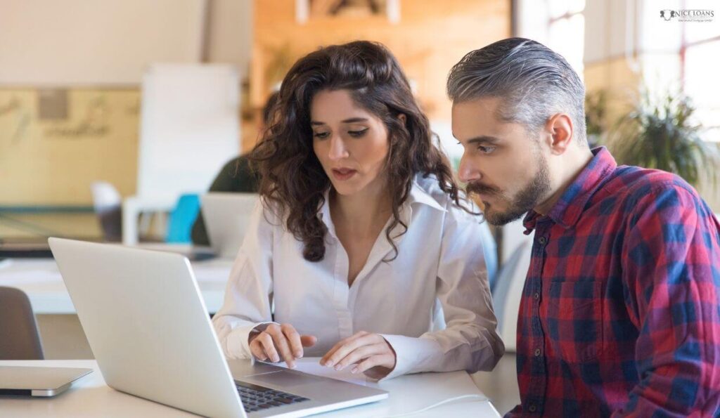 two coworkers working on a laptop.

