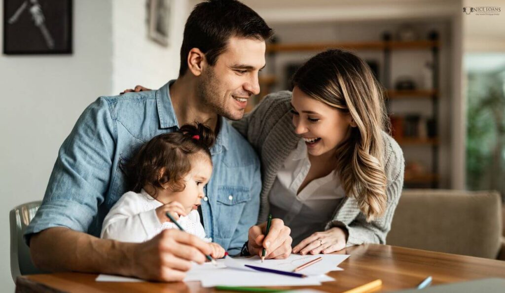 a family of three at the table happily colouring a drawing book. 