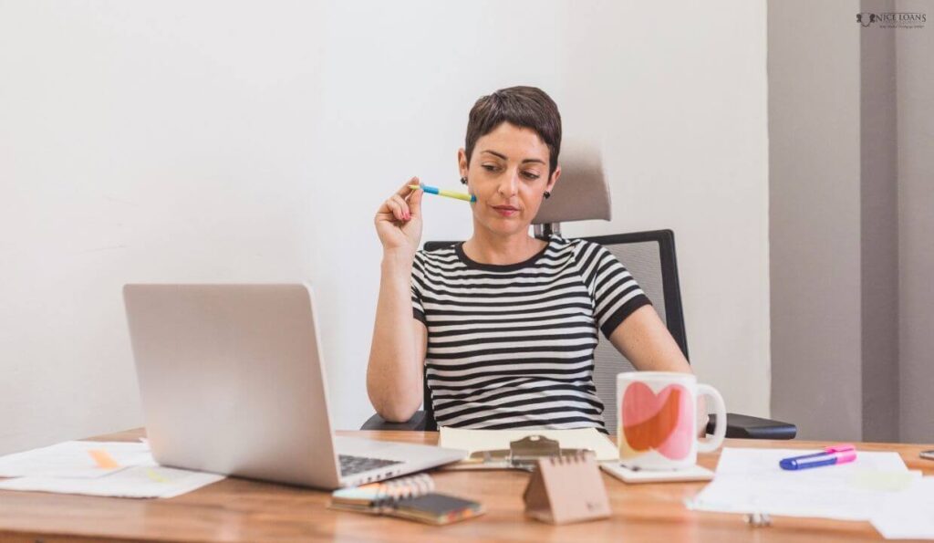 an office worker looking at her laptop, thinking as she worked. 