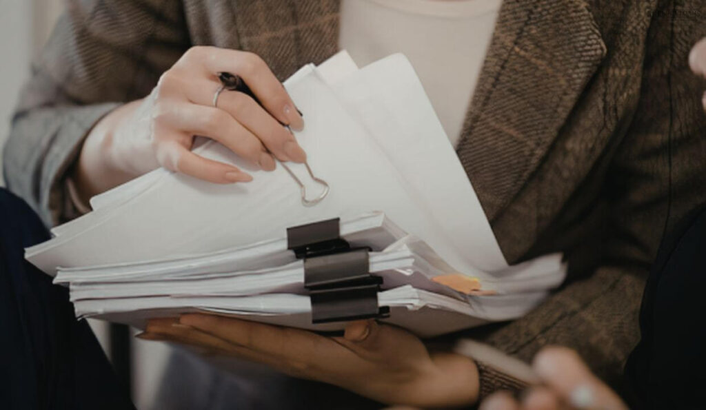 Two hands holding a stack of papers together. 