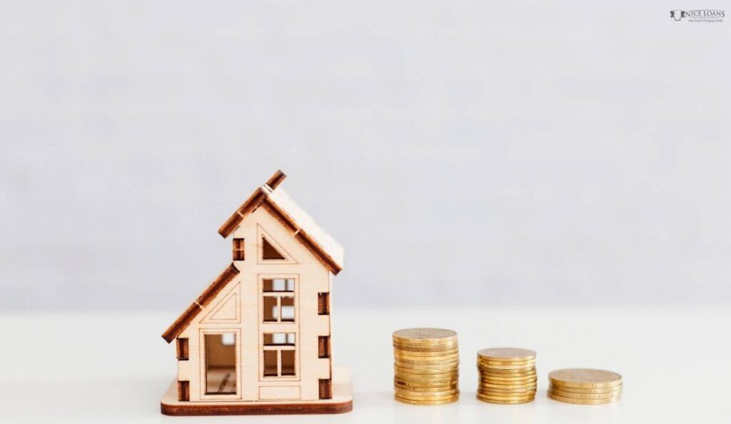 a wooden model home beside three stack of coins.