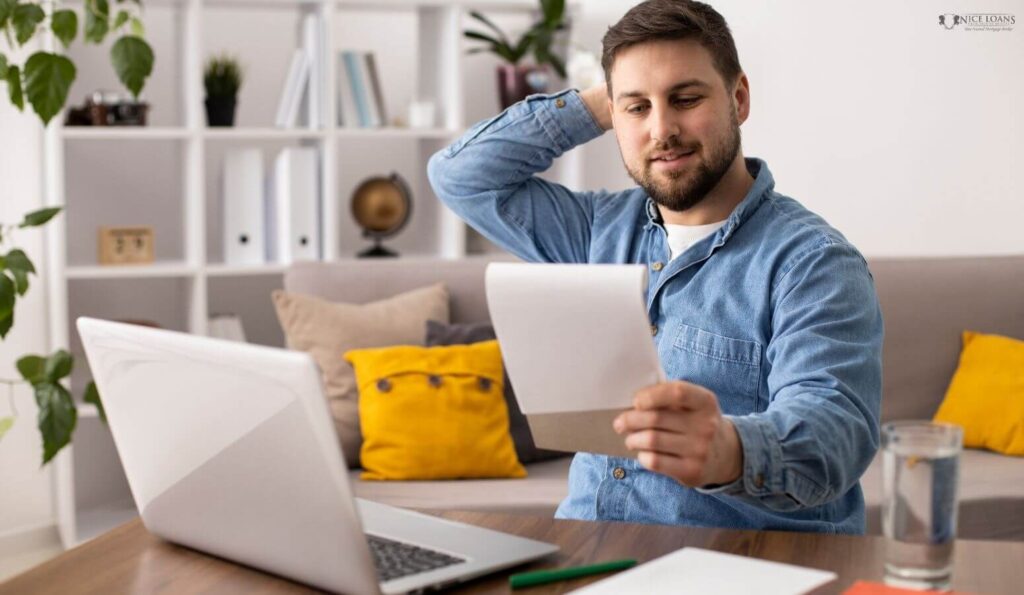 a man with his laptop open holding a notebook, comparing owner occupied vs investment loans