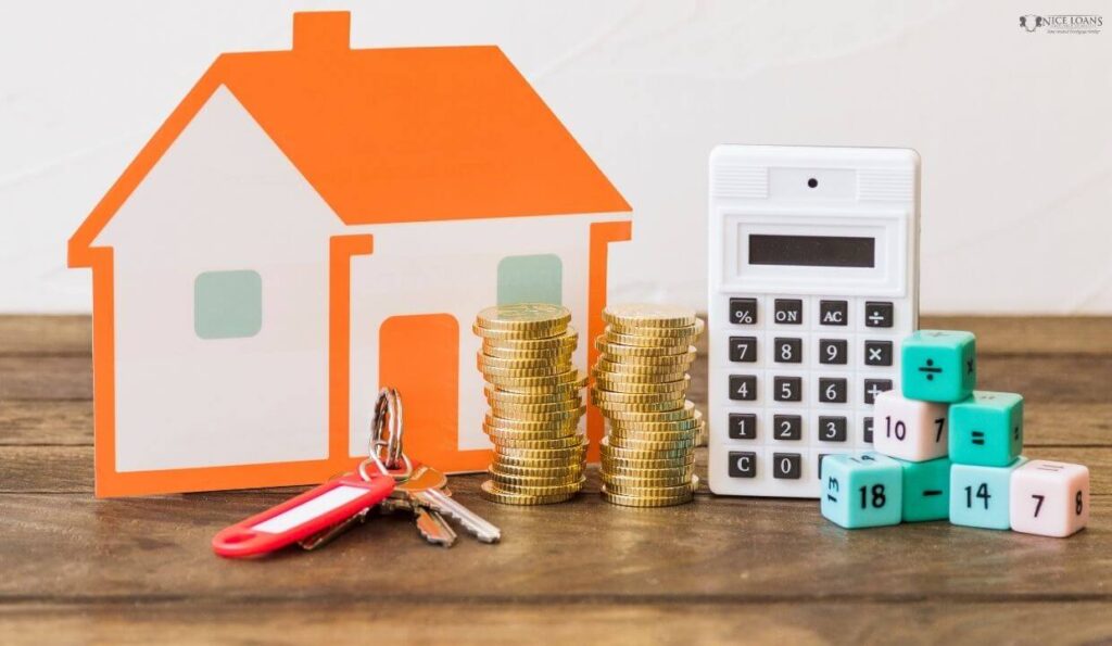 a house with house keys stacked coins calculator and math blocks on a wooden table